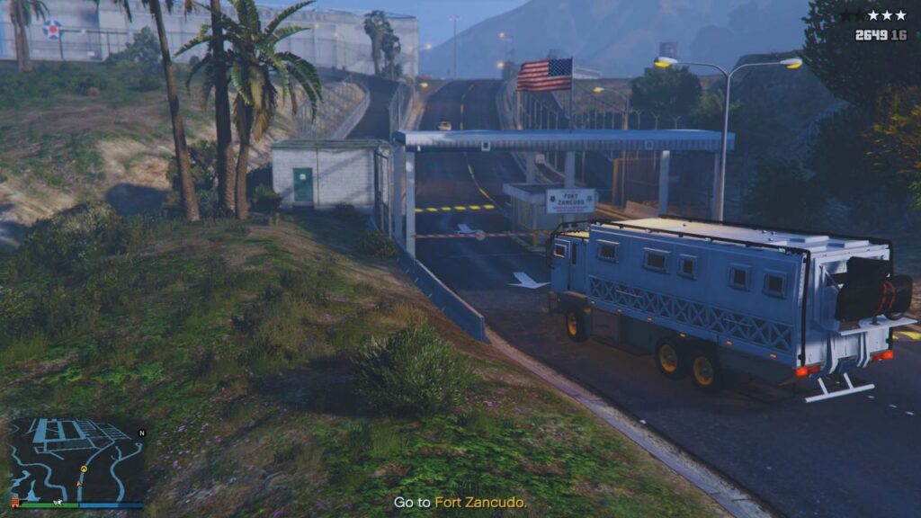 The player driving a Brickade 6x6 truck at the entrance of Fort Zancudo military base.